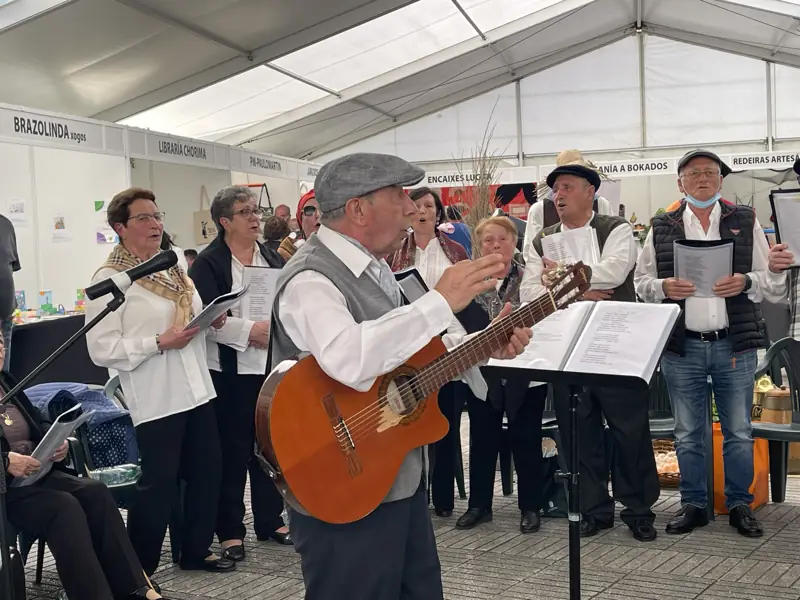 Miguel Martín Treus dirixe co brazo en alto mentres toca a guitarra diante do grupo